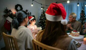 süß wenig Mädchen im Santa Hut Öffnung Weihnachten Geschenk und lächelnd. foto