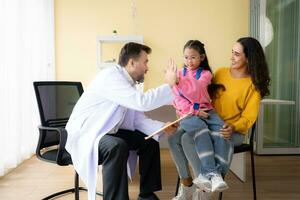 Arzt geben hoch fünf zu ein Mama von wenig Mädchen während Sitzung auf Mutter Runde beim Krankenhaus foto