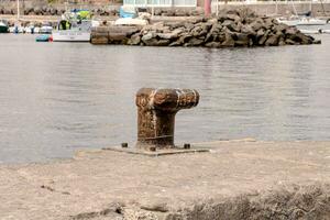 ein rostig Metall Rohr Sitzung auf das Kante von ein Seebrücke foto