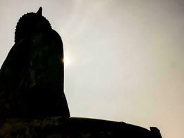 Silhouette von ein groß Buddha Statue im Vorderseite von ein wolkig Himmel foto