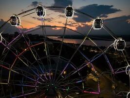 schön Sonnenuntergang Über das Stadt mit ein beleuchtet Ferris Rad. foto