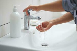 Nahansicht Frau Waschen Hände unter Laufen Wasser, mit Antiseptikum antibakteriell Reinigung Flüssigkeit Seife foto