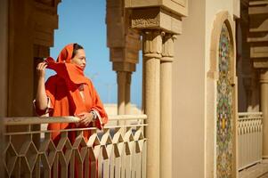 schön Muslim Frau Stehen zwischen Marmor Säulen, suchen in das Distanz, während Wind weht Schal auf ihr Kopf foto