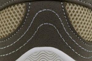 Fragment von ein braun Stoff Sneaker mit Weiß Nähen. das Textur von das Material von Sport Schuhe foto