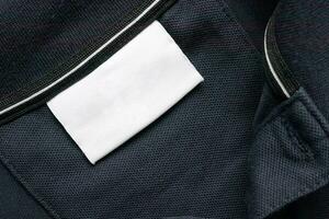 leer Weiß Wäsche Pflege Kleider Etikette auf schwarz Hemd Stoff Textur Hintergrund foto