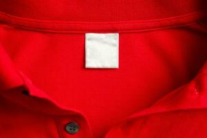leer Weiß Wäsche Pflege Kleider Etikette auf rot Hemd Stoff Textur Hintergrund foto
