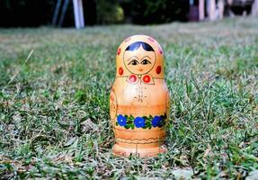 ein klein hölzern Puppe Sitzung im das Gras foto