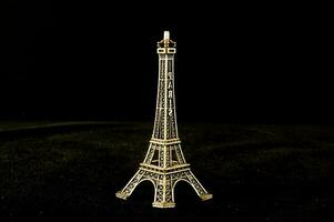 ein klein Gold Eiffel Turm auf ein schwarz Hintergrund foto