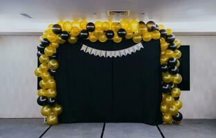 Geburtstag Dekoration drinnen mit Gelb und schwarz Luftballons, grau Teppich, schwarz Stoff und Weiß Mauer Hintergrund. foto