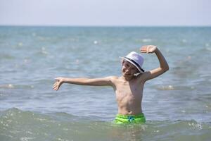 ein glücklich Junge im ein Weiß Panama schwimmt im das Meer. foto