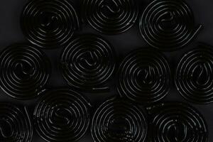Spiral- schwarz Hintergrund. Lakritze Süßigkeiten im das bilden von ein Spiral- Nahansicht. foto