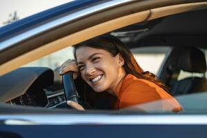 junge Frau, die ihr neues Auto umarmt. Aufgeregte junge Frau und ihr neues Auto drinnen. junge und fröhliche frau, die das neue auto genießt, das das lenkrad umarmt, das innen sitzt foto