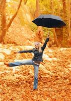 Süss Mädchen Springen mit Regenschirm foto