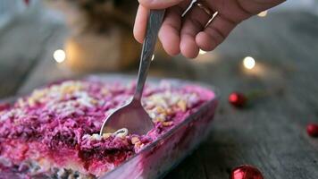 hausgemacht Neu Jahr ist ein Hering Salat unter ein Pelz Mantel auf ein hölzern Hintergrund. ein des Mannes Hand liegt ein Russisch traditionell Weihnachten Salat mit ein Löffel. foto