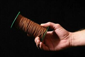 ein Hand halten ein Spule von braun Kabel foto