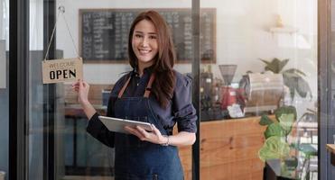 Porträt einer lächelnden asiatischen Unternehmerin, die hinter ihrem Café steht foto
