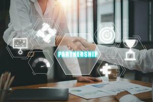 Partnerschaft Konzept, Geschäft Mannschaft Herstellung Handschlag mit seine Partner im Büro Schreibtisch mit Partnerschaft Symbol auf virtuell Bildschirm. foto