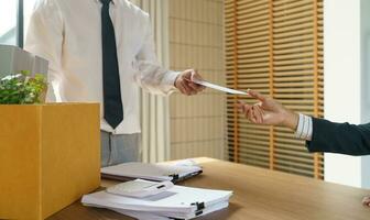 Verlassen Job Geschäft Mann Senden Rücktritt Brief und Verpackung Zeug zurücktreten drücken oder Tragen Geschäft Karton Box im Büro. Veränderung von Job oder gefeuert von Unternehmen. foto