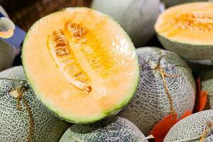 des Mannes Hand pflücken ein Melone von das Supermarkt Korb. geschnitten Cantaloup-Melone Melone. foto