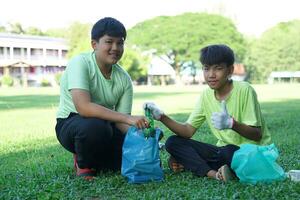 ein asiatisch Junge ist ein Schüler im das Umwelt Verein und seine freunde Hilfe sammeln und Sortieren Abfall Plastik Wasser Flaschen und Glas Flaschen zum Recycling oder Wiederverwendung. im das Konzept von Speichern das Welt. foto