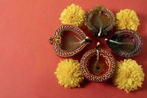 glücklich Diwali und karthika tief - - bunt Lehm deepams mit Blumen auf rot Hintergrund foto
