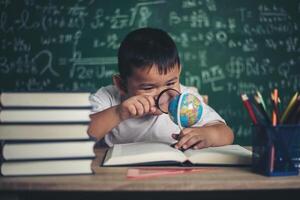 Kind beobachtet oder studiert pädagogisches Globusmodell im Klassenzimmer. foto
