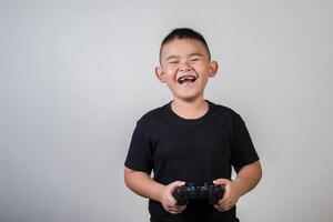 glücklicher Junge spielt Spielcomputer mit einem Controller im Studiofoto foto