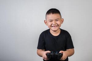 glücklicher Junge spielt Spielcomputer mit einem Controller im Studiofoto foto