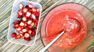 Erdbeerpüree und Beeren werden in Lebensmittelbehälter gelegt foto