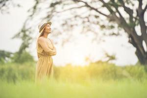 junge Frau, die glückliche Zeit im Grasfeld steht. foto
