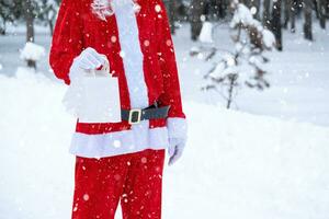 weihnachtsmann im freien im winter und schnee, der handpapiertüten mit handwerksgeschenk, lebensmittellieferung übergibt. Einkaufen, Verpackungsrecycling, Handarbeit, Lieferung für Weihnachten und Neujahr foto