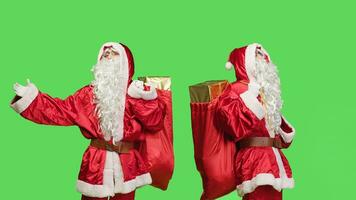 Mann Schauspielkunst mögen Santa claus mit Sack von Spielzeuge, Tragen Geschenke und die Geschenke Über grüner Bildschirm Hintergrund. Heilige Nick Verbreitung Weihnachten Geist auf Winter Feiertage, tragen Tasche auf Kamera. foto