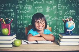 Porträt eines lächelnden Schulmädchens, das mit Büchern am Tisch sitzt