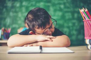 Junge schläft auf den Büchern im Klassenzimmer. foto