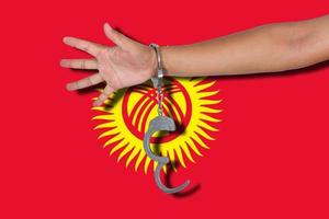 Handschellen mit Hand auf kirgisischer Flagge foto