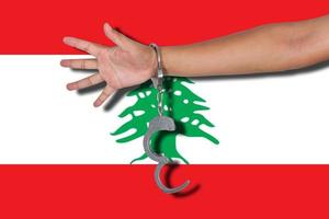 Handschellen mit Hand auf libanesischer Flagge foto