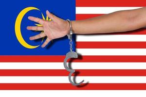 Handschellen mit Hand auf Malaysia-Flagge foto