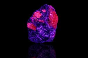 Makro Mineral Stein Alexandrit unter ultraviolett Licht auf ein schwarz Hintergrund foto