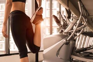 Nahaufnahme der Schönheitsfrau, die die Beine im Training-Fitnessstudio ausdehnt? foto