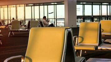 Flughafen warten Bereich mit Gelb Stühle und verschwommen Menschen im das Hintergrund foto