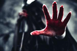 Hexe zeigt blutige Hand mit Schnitter foto