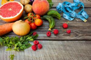 Früchte, Gemüse und im messen Band im Diät auf hölzern Hintergrund foto