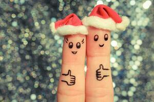 Finger Kunst von Paar feiert Weihnachten. Konzept von Mann und Frau Lachen im Neu Jahr Hüte. glücklich Paar zeigen Daumen hoch. getönt Bild. foto