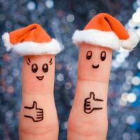 Finger Kunst von Paar feiert Weihnachten. Konzept von Mann und Frau Lachen im Neu Jahr Hüte. glücklich Paar zeigen Daumen hoch. getönt Bild. foto