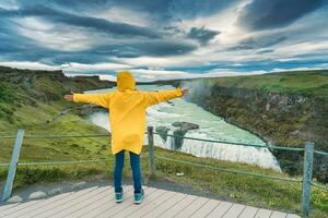 weiblich Tourist genießen auf Standpunkt von gullfoss Wasserfall mit hvita Fluss fließend im Schlucht beim Island foto