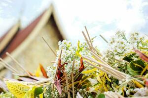 nahaufnahme und ernte haufen duftender blumen mit weihrauch zur anbetung des buddha auf verschwommenem thailändischem tempelheiligtum und blauem hintergrund. foto