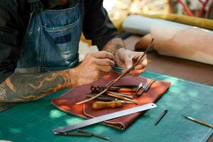 Nahansicht und Ernte Hände von Leder Handwerker ist Arbeiten schwer zu nähen ein Leder Produkt zum ein Kunde. foto