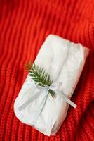 ein hausgemacht Weihnachten Stollen versiegelt im Weiß Kunst Papier Lügen auf ein rot gestrickt Stoff. Geschenk wickeln. foto