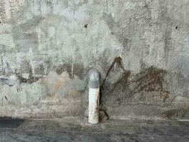 unrein Beton Mauer draussen mit grungy texturiert beflecken isoliert auf horizontal Verhältnis und Wasser Rohr gehen Nieder zu das Boden Objekt. foto