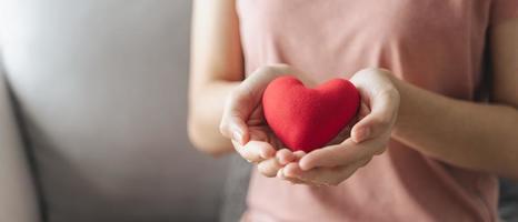 Frau hält rotes Herz, Liebe, Krankenversicherung, Spende, glückliche Nächstenliebe foto